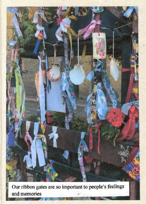 Decorative gate covered with colourful ribbons, fabric strips, shells, flowers, and small ornaments, with handwritten text reading: ‘Our ribbon gates are so important to people’s feelings and memories.’